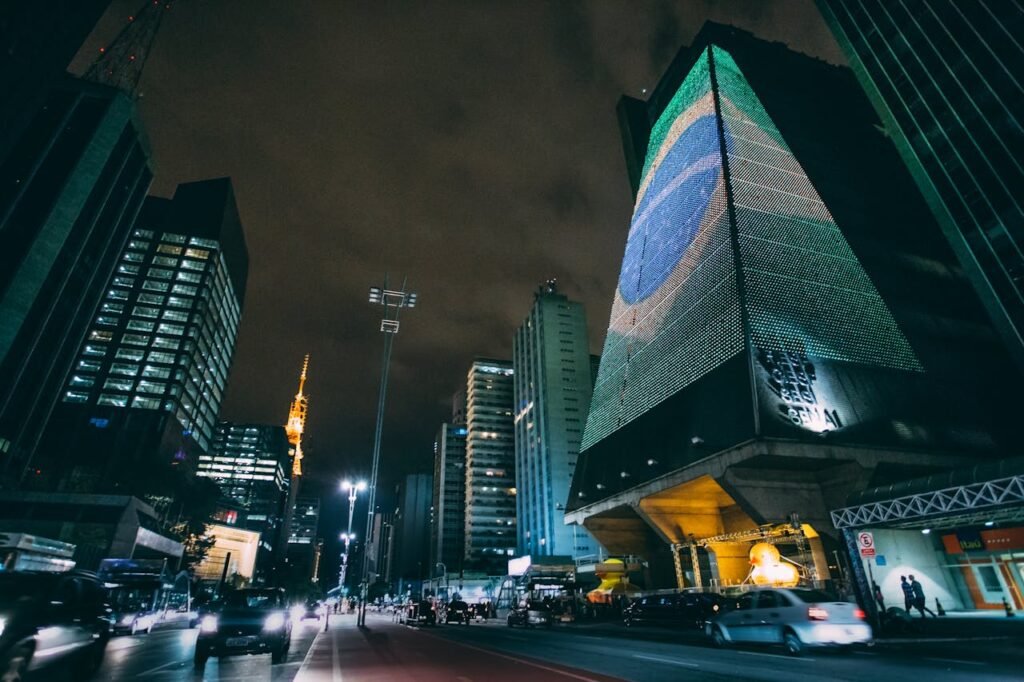 Cars Traveling on Road Between Buildings during Nighttime